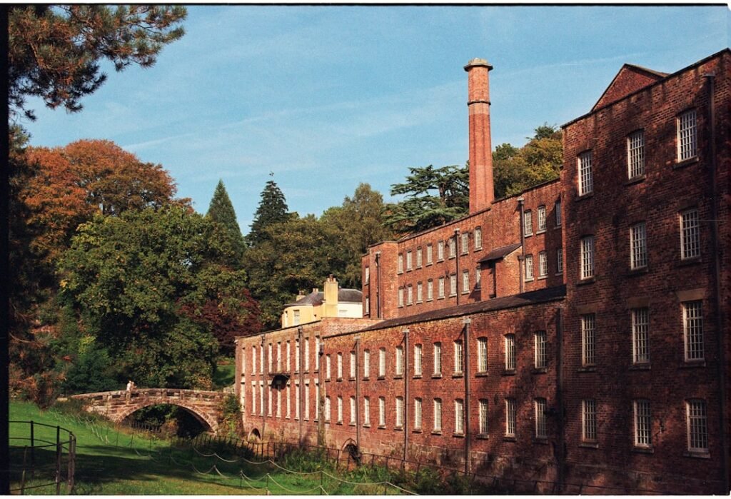 Old brick factory building with a tall chimney.