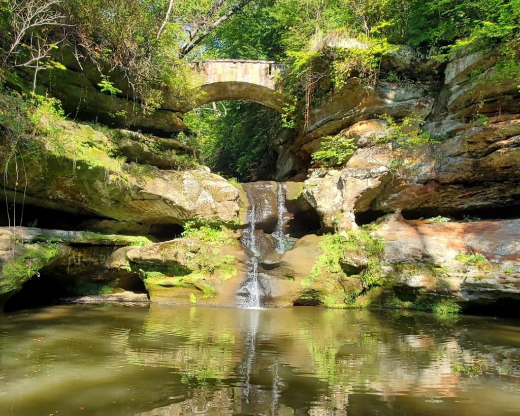 a waterfall with a bridge in the background