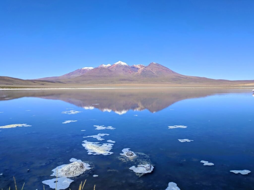 body of water near mountain under blue sky during daytime
