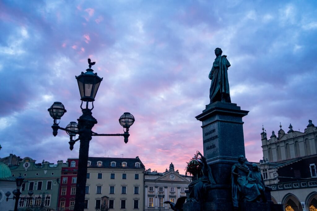 Historic statue and lamppost against a vibrant sunset sky
